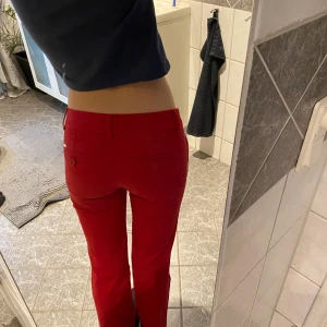 Röda byxor med låg midja - Snygga röda byxor med låg midja och raka ben. Byxorna har knappar och en stilren design som passar till många olika outfits.
