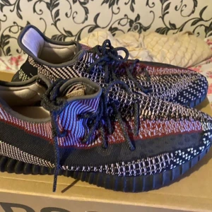 Adidas Yeezy Boost 350 V2 - Säljer ett par Adidas Yeezy Boost 350 V2 med ett unikt mönster i svart, röd och blå. köpta för 3200 på footlocker.