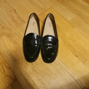 Svarta loafers från Bronx - Snygga svarta loafers i lack från Bronx. Perfekta för en stilren look med en glansig finish. Passar bra till både vardag och mer uppklädda tillfällen.