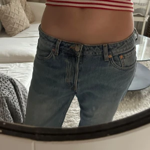 Blå jeans - Säljer ett par klassiska blå jeans med låg midja och rak passform. Perfekta för en avslappnad stil. De har en traditionell femficksdesign och knappgylf. Modellen PIN från weekday