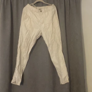 Linne byxor från h&m - Säljer ett par beige byxor från H&M i regular fit. Byxorna har en knapp och dragkedja framtill och är tillverkade i ett lätt och bekvämt material.