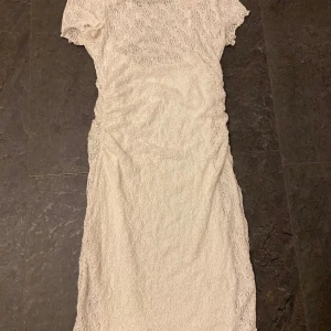 Vit spetsklänning - Elegant vit spetsklänning med korta ärmar och en smickrande passform. Perfekt för sommarens festligheter. Använd en gång.