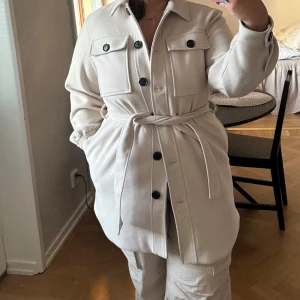 Ellos kappa - En jättefin beige kappa med knappar och knytning! Endast använd 1-2 gånger och är i mycket fint skick☺️ Kappan kommer från Ellos och är i storlek 42! Superfin nu till hösten😻 Nypris 800 kr.