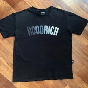 Svart t-shirt från Hoodrich - Säljer en svart t-shirt från Hoodrich med stort tryck på framsidan. Storleken är S men funkar för M ochså. Helt nya, nytt priss 600kr Mitt pris 199kr.T-shirten är perfekt för en avslappnad stil och passar till vardags.