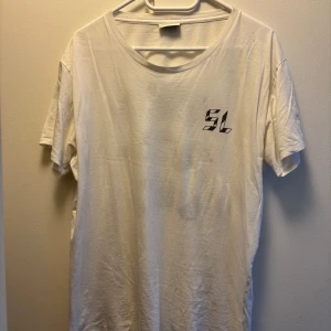 Saint Laurent  - Snygg tisha från saint lauren. Några små hål men de gör att den ser lite snyggare ut kanske? Size M, bra skick annars. Otroligt skön och snygg passform. Nypris 3k. 