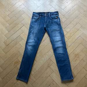 Säljer ett par snygga blå jeans från Replay i modellen anbass. De har en klassisk femficksdesign med en knapp och dragkedja framtill. De är i väldigt bra skick