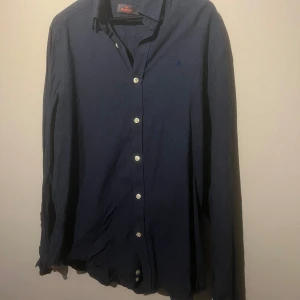 Mörkblå skjorta från Morris - Säljer en snygg mörkblå skjorta från Morris. Den har långa ärmar och knappar fram. Perfekt för både vardag och fest. Skjortan är i bra skick och redo för en ny ägare!