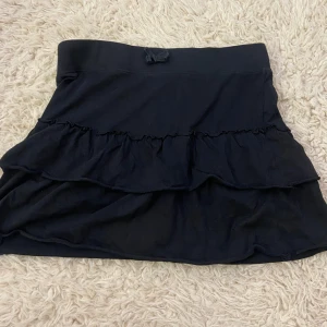 Svart kort kjol  - Supergulliga svart kort kjol med lite volanger och en rosett. Från Lindex i storlek 170 jag skulle säga att den passar xs/s