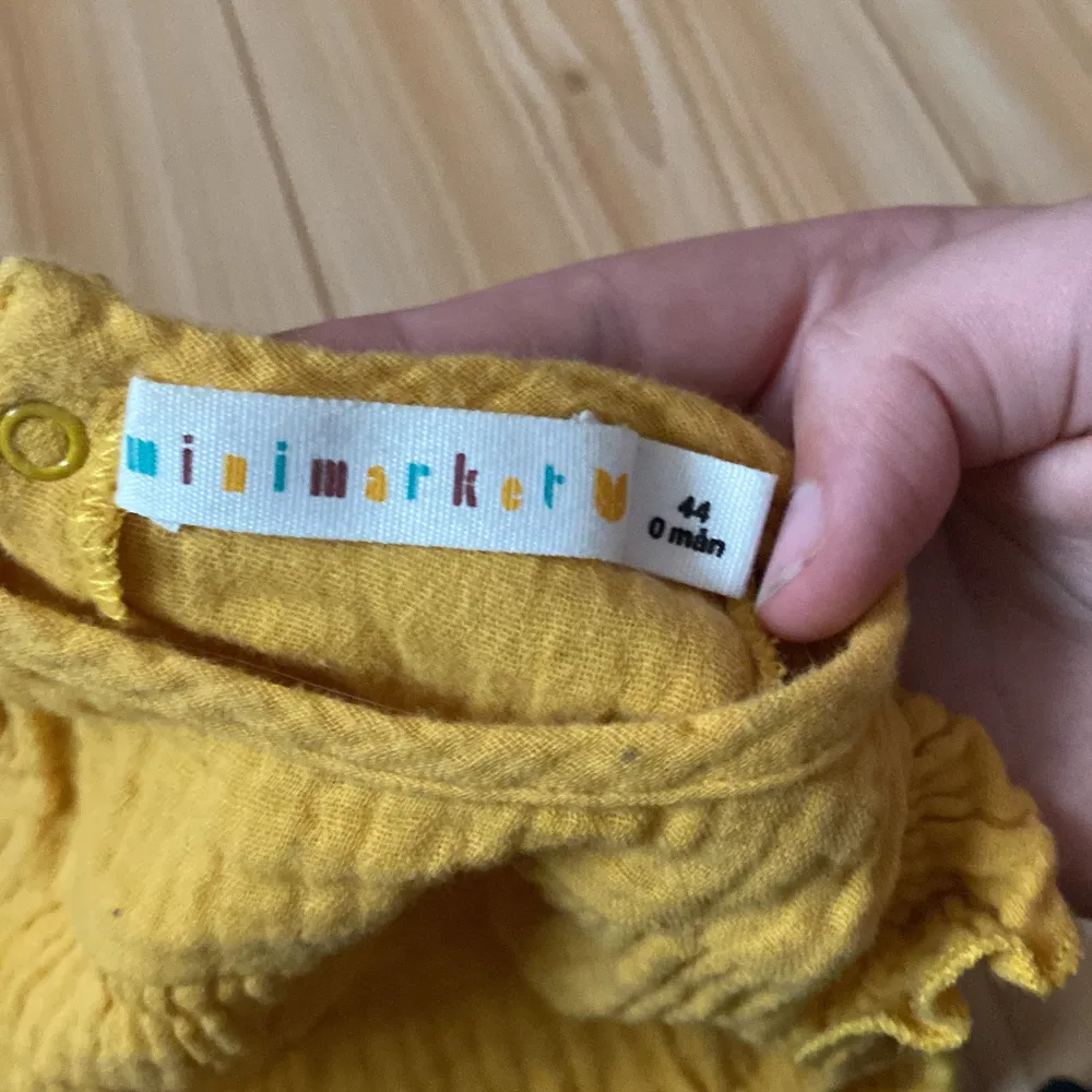 Säljer en supergullig gul babybody från Minimarket i storlek 44. Den är gjord av mjukt och bekvämt material, perfekt för de minsta. Bodyn har söta volangdetaljer vid ärmarna och praktiska tryckknappar i grenen för enkel på- och avklädning. Perfekt för sommarens varma dagar! 🌞. Klänningar.