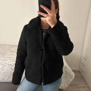 Svart teddyjacka från River Island - Mysig svart teddyjacka från River Island, perfekt för kyliga dagar. Jag säljer denna jackan då den inte är min stil längre och kommer inte längre till användning. 