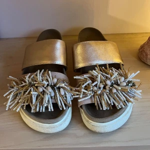 Inuikii tofflor  - Tofflor från Inuikii med dekorativa pärlor och fransar på ovandelen. Nypris 2000kr. Några rosa stenar har lossnat på ena skon, inget man tänker på så jätte mycket. Därav priset🌸