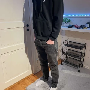 Svarta jeans från J.Lindeberg - Snygga svarta jeans från J.Lindeberg i en klassisk straight passform. De har en stilren design med dragkedja och knapp framtill. Perfekta för en stilren look.