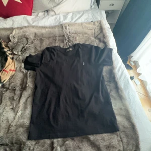 Svart t-shirt från Ralph Lauren - Snygg svart t-shirt från Ralph Lauren med en liten broderad logga på bröstet. Perfekt för en stilren look. Passar till många olika outfits.