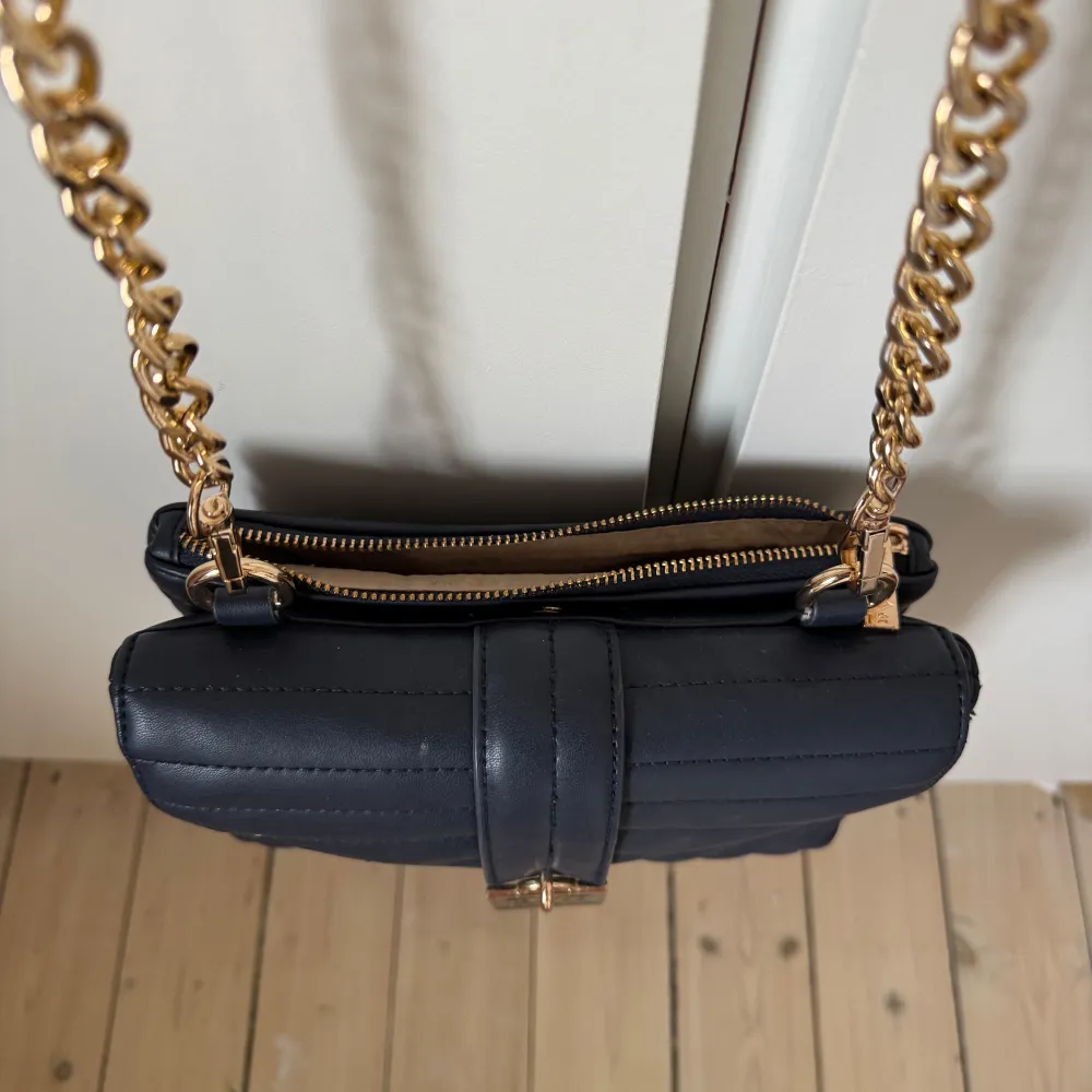 Snygg quiltad axelväska från 19V69 Italia med guldfärgad kedja och detaljer. Väskan har en dragkedja och en detalj framtill. Perfekt för att ge en elegant touch till din outfit. Den är amvänd några gånger och har lite småskavanker men annars i toppskick! ☺️. Laukut & Käsilaukut.