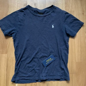 Mörkblå t-shirt från Polo Ralph Lauren - Säljer en snygg mörkblå t-shirt från Polo Ralph Lauren. T-shirten är kortärmad och tillverkad i mjuk bomull. Perfekt för en avslappnad stil. Väldigt bra skick! Priset går att diskuteras storleken är 140 men passar större 