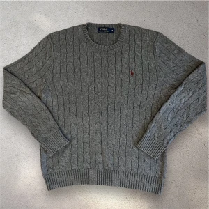 Grå kabelstickad tröja från Polo Ralph Lauren - En riktigt snygg kabelknit tröja från ralph lauren. Fint skick. Modellen är 180 cm lång och väger 65 kg. Skriv vid frågor!