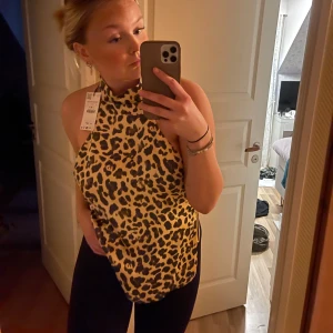 Leopardmönstrad halterneck topp - Säljer en snygg leopardmönstrad halterneck topp i satin med knytning i ryggen. Passar perfekt till fest. Endast testad med prislapp kvar.
