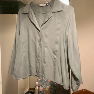 Grå blus från Weekday strl 36 - Snygg mintgrön blus från Weekday i ett mjukt och lätt material. Blusen har armbågslånga ärmar och knappar framtill, vilket ger en stilren look. Perfekt för en chic och avslappnad stil.