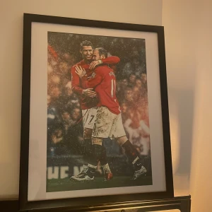 Inramad fotbollsposter - Inramad poster med fotbollsmotiv. Bilden visar Rooney och Ronaldo som kramas 