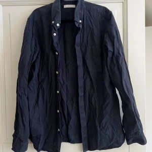 Mörkblå skjorta från Premium by Jack & Jones - Snygg mörkblå skjorta från Premium by Jack & Jones. Skjortan har långa ärmar och knappar framtill. Perfekt för en stilren look.