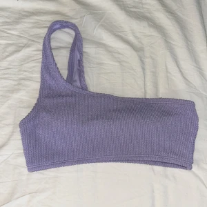 Lila ribbad bikiniöverdel - Snygg lila bikiniöverdel med ett axelband och ribbad textur. Den har använts ett fåtal gånger med är i bra skick.