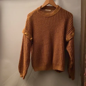 Brun stickad tröja från Hailys - Säljer en snygg brun stickad tröja från Hailys. Tröjan har långa ärmar med dekorativa knappar på axlarna och en rund halsringning. Lite nopprig men inget som är märkvärdigt💗säljer då den inte kommer till användning☺️skriv om ni har några funderingar ☺️
