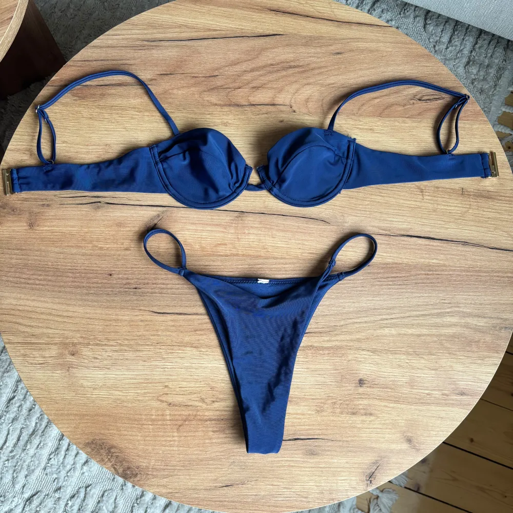 Snygg mörkblå bikini med bygel-bh och justerbara axelband. Trosorna har en klassisk design med smala sidor. Perfekt för en dag på stranden eller vid poolen. Alla lappar är bortklippta men bikinin är oanvänd.. Muu.
