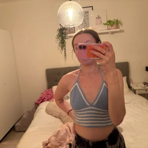 Blå- och vitrandig stickad halterneck-topp - Säljer en söt blå- och vitrandig virkad halterneck-topp. Toppen är croppad och har en knytning i nacken. Perfekt för sommardagar! Egengjord och kan göra liknande toppar på beställning efter önskemål och färg 