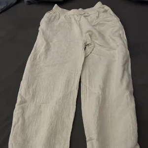 Beige linnebyxor - Säljer ett par bekväma beige linnebyxor med elastisk midja. Perfekta för en avslappnad stil och sköna att bära under varma dagar.