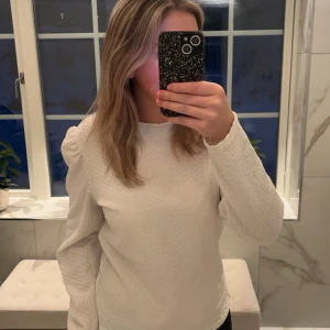 Vit långärmad tröja - Säljer en stilren vit långärmad tröja med en enkel och elegant design. Tröjan har en rund hals och är tillverkad i ett mjukt material som ger en bekväm passform.