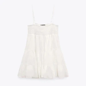 Vit klänning med smala axelband - Söt vit klänning med smala axelband och en luftig passform. Perfekt för varma sommardagar. Den har en enkel och stilren design som gör den lätt att matcha med olika accessoarer.