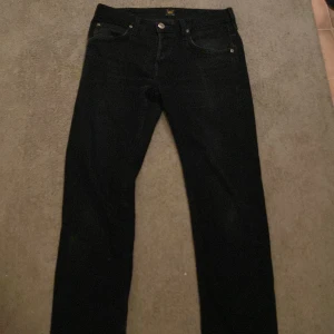 Svarta jeans från Lee - Snygga svarta jeans från Lee med klassisk femficksdesign. De har en rak passform och är perfekta för en stilren look. Jeansen har en knappgylf och är tillverkade i ett slitstarkt material. 32 L och och 30 M
