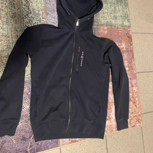 Mörk blå zip hoodie från Sail racing - Säljer en stilren mörk blå hoodie från Sail Racing ! Helt ny använd cirka 5 gånger, storlek L men passar även M!