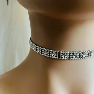 Made by prisförslag- Glittrig choker i silver - Snygg och elegant choker i silver med glittrande detaljer. Perfekt för att ge en extra touch till din outfit. Den har en rad av små, gnistrande stjärnor som fångar ljuset vackert.
