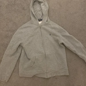 Grå hoodie från Polo Ralph Lauren - Säljer en Ralph lauren zip hoodie i jätte bra skick, köpt för cirka två månaders sedan och knappt använd, som ni ser på bilderna, storleken är XL barn så den sitter ungefär som s, priset kan gå att diskuteras vid snabb affär