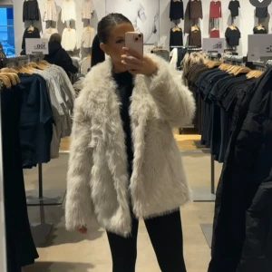 Vit pälsjacka från lager 157 - Säljer en fluffig och stilren vit pälsjacka med långärmad design. Perfekt för att hålla sig varm och trendig under kyliga dagar. Jackan har en klassisk passform och är lätt att matcha med olika outfits. Helt ny