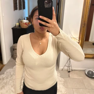 Beige stickad tröja - Säljer en beige stickad  tröja med v-ringning Från vero moda. På en av bilderna kan ni se att det finns en liten fläck på ärmen.