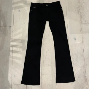 Svarta lågmidjade jeans med detaljer - Midjemått rakt över: 40cm, Grenhöjd: 23cm, Innerbenslängd: 83cm 🩷Snygga svarta lågmidjade bootcut byxor med unika broderade detaljer och glittrande stenar på bakfickorna. Perfekta för att ge en extra edge till din outfit. Byxorna har en klassisk och lågmidjad passform med knapp och dragkedja framtill. Säljer då de ej passar längre 💛