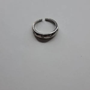 Silverring med stjärndetaljer - Snygg och stilren silverring med ingraverade stjärnor runt om. Perfekt för att ge en extra touch till din outfit. Ringen är justerbar och passar de flesta storlekar. PRISET KAN DISKUTERAS