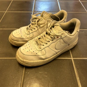 Vita Nike Air Force sneakers - Säljer ett par klassiska vita Nike Air Force sneakers. Skorna har snörning och är tillverkade i skinn. Perfekta för en avslappnad stil.