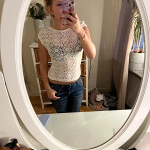 Vit spetstopp  - Säljer en söt vit spetstopp från Stradivarius med en öppen rygg. Toppen är ärmlöst och har ett vackert blommönster. Perfekt för en somrig look eller att bära under en kavaj. Är i ett mycket bra skick då jag använt den fåtal gånger.