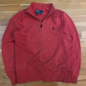 Röd tröja från Polo Ralph Lauren - Säljer en snygg röd tröja från Polo Ralph Lauren i 100% bomull. Tröjan har en dragkedja vid halsen och det klassiska broderade logotypen på bröstet. Perfekt för en stilren look!