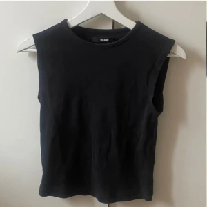 Svart ärmlös topp från Bik Bok - Snygg och enkel svart ärmlös topp från Bik Bok i storlek S. Perfekt för lager-på-lager eller att bära som den är. Gjord i mjukt material för en bekväm passform. Ett måste i garderoben! 2 första bilderna e lånade
