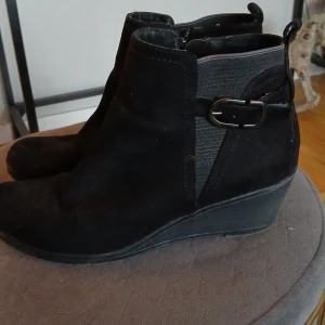 Svarta boots med kilklack - Snygga svarta boots i mocka med kilklack och dragkedja på sidan. Perfekta för höst och vinter. Storlek 42. Supersköna.