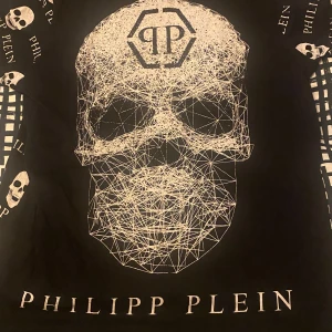 Philipp plein t-shirt  - Cool svart t-shirt från Philipp Plein med ett unikt dödskallemönster och logotyp. Perfekt för dig som vill sticka ut med en edgy stil. T-shirten har korta ärmar och är gjord i ett bekvämt material.