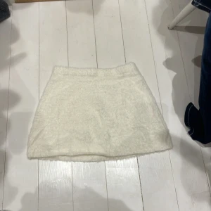 Vit kjol från Zara - Säljer en fluffig vit kjol från Zara i storlek 164. Kjolen har en mjuk och mysig textur, perfekt för kyligare dagar. Den är kort och har en elastisk midja för bekväm passform. Aldrig använd, köpt för 400kr