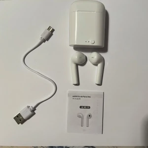 Trådlösa vita hörlurar med laddningsetui - Nya hörlurar, dom är lite större än vanliga AirPods. Inkluderar en USB-laddningskabel och manual. Man kan lyssna musik och prata i dom. 