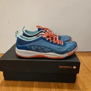 Blå och turkosa sneakers från Merrell - Snygga och bekväma sneakers från Merrell i blått och turkost med orange snörning. Perfekta för träning eller vardagsbruk. Skorna har en lätt och flexibel sula för optimal komfort.