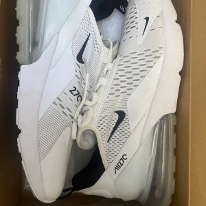 Nike Air Max 270 i vitt - Snygga och moderna Nike Air Max 270 sneakers i vitt med svarta detaljer. Skorna har en luftig mesh-ovandel och den ikoniska Air Max-sulan för extra komfort. Perfekta för all användning. helt nya använda 2 gånger men köpte ett par andra skor och därför säljer jag dem. Storlek 42