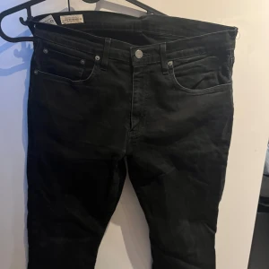 Svarta jeans från Levi's - Snygga svarta jeans från Levi's med klassisk femficksdesign och knappgylf. Perfekta för en stilren look. Storlek W 32 L 34